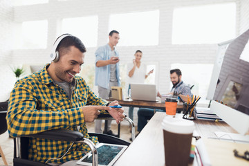 A man in a wheelchair is working in a modern office.
