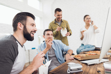 Office workers and man in a wheelchair look at the computer screen and laugh.