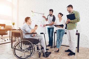 Office workers and man in a wheelchair discussing business moments while working in a modern office.