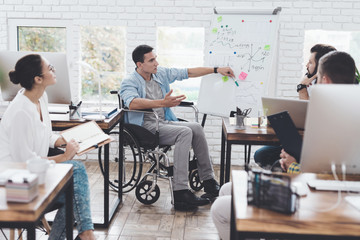 Office workers and man in a wheelchair discussing business moments in a modern office.