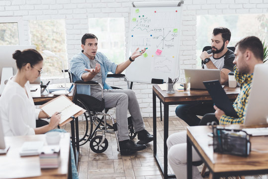 Office workers and man in a wheelchair discussing business moments in a modern office.