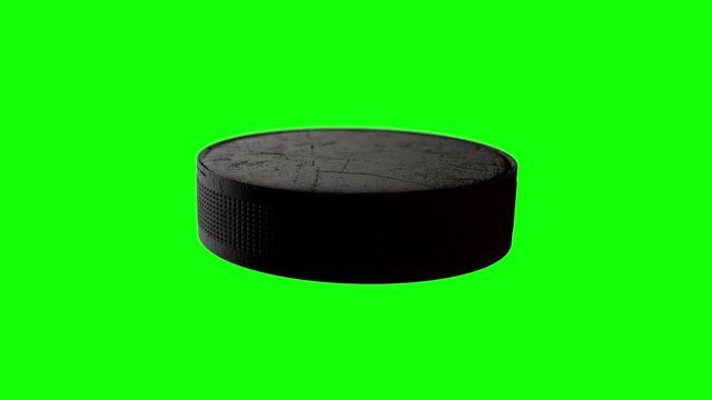 A loop able animation of a hockey puck spinning in slow motion on a green screen background