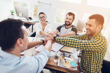 A group of young people discussing something in the office. They are showing a teamwork.
