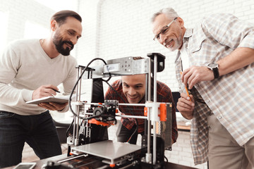 Three men set up a self-made 3d printer to print the form. They are preparing to launch the device...