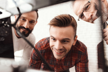 Three men set up a self-made 3d printer to print the form. They are preparing to launch the device for the first time.