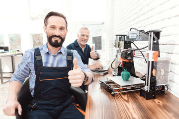 An engineer in a working overall posing in a technical laboratory. Behind it is a 3d printer.