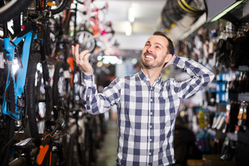 Biker is choosing in sports store convenient bike