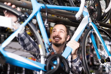 man checks bicycle frame in shop when choosing bike