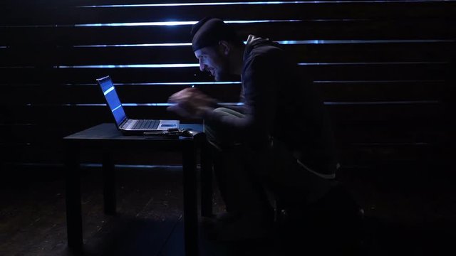 comic funny hacker commits a cyber attack with a laptop and a gun in his hands