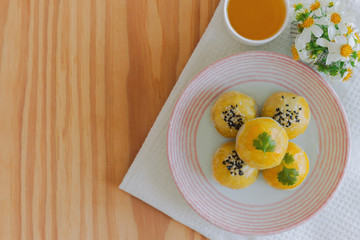 Chinese pastry or moon cake filled with mung bean paste and salted egg yolk on ceramic plate served with tea on wood table in top view flat lay with copy space. Homemade bakery concept.