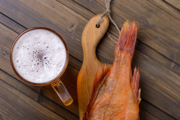 Closeup fresh beer with fish on wooden table in pub
