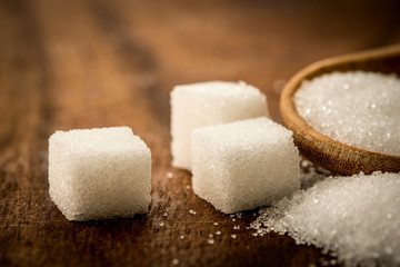 Close up a sugar cubes and cane in wooden spoon on the table ,retro color tone