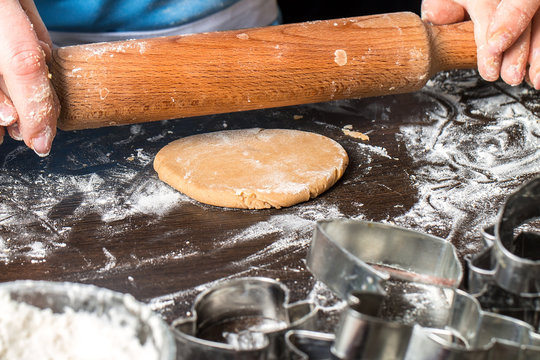 Hands of little girl sheeting dough with rolling pin