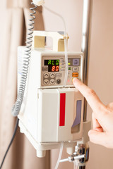 Hand of doctor control IV on infusion pump.
