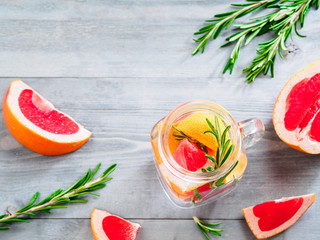 infused detox water with grapefruit and rosemary in mason jar bottle on gray wooden table. diet healthy eating and weight loss concept, copy space for text. Top view