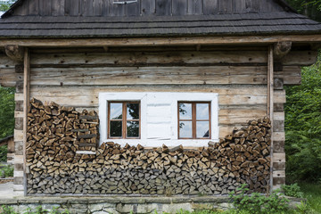 An old wooden building with windows and stacked wood.