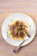 Meatballs with mushroom gravy and mashed potato on white plate. View from above, top studio shot, vertical