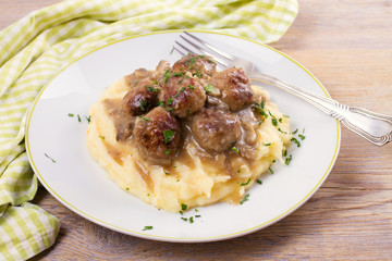 Meatballs with mushroom gravy and mashed potato on white plate, horizontal