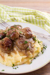 Meatballs with mushroom gravy and mashed potato on white plate, vertical