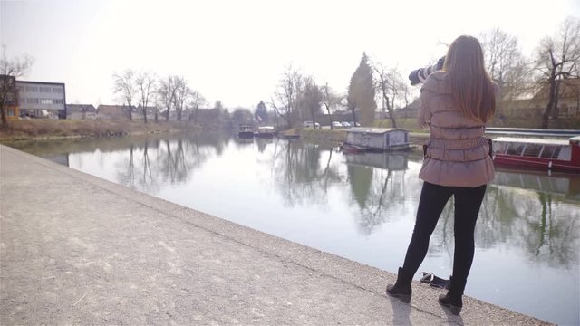 Female photographer by the river on concrete bank 4K