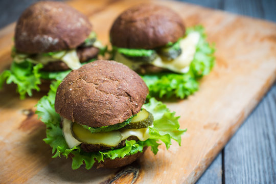 Burgers on the dark rustic background. Selective focus. Shallow depth of field. Black and white image.