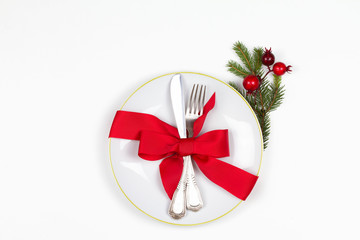 Christmas table place setting with plate, cutlery, pine branches,  ribbon and red berries. Winter holidays and festive background. Christmas eve dinner, New Year food lunch. View from above, top
