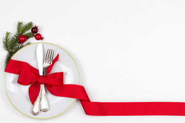Christmas table place setting with plate, cutlery, pine branches,  ribbon and red berries. Winter holidays and festive background. Christmas eve dinner, New Year food lunch. View from above, top - Powered by Adobe