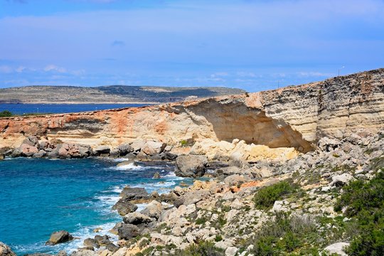Rocky coastline with Comino to the rear, Paradise Bay, Malta.