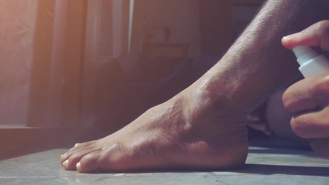 Men have an ankle injury.Hand spraying medicine on the pain.Selective focus,Human health care and medicine concept.