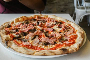 thin crust ham and mushroom homemade pizza on table for lunch in Italian restaurant