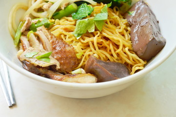 dry Chinese egg noodles topping duck meat and bean sprout on bowl and stainless chopsticks