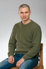 a stylish young man in a green military style sweater. Studio.