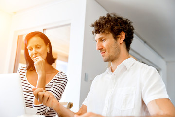 Happy modern couple working on laptop at home