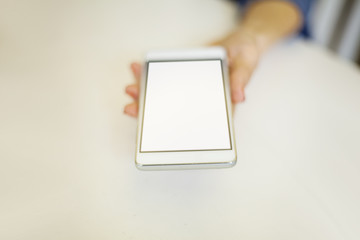 A female hand holds a phone with a white screen for advertising.