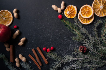 Christmas composition.Noel. tree branches, cinnamon, orange, nuts, Apple on black background. Top view, flat lay.