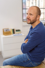 Fototapeta premium mann sitzt entspannt im büro auf dem tisch und schaut zur seite