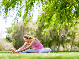 Naklejka na ściany i meble Young woman doing yoga in the park