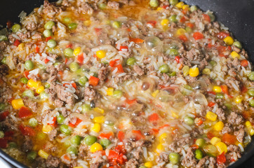 Minced meat with rice and vegetables in a frying pan. Close up