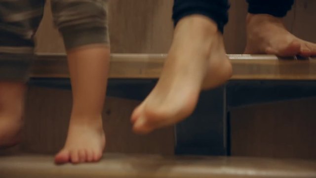 Close-up of feet of mother and baby doing first steps around the house. Feet coming up the stairs.
