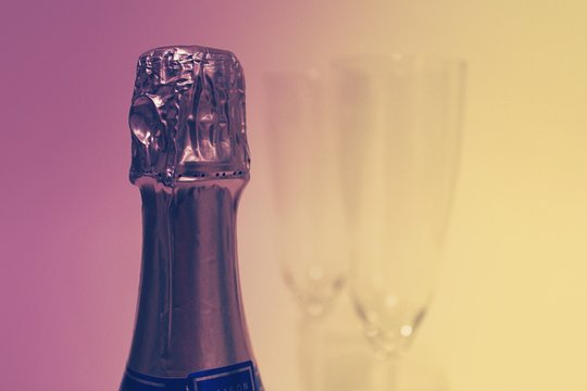 Purple and Yellow Color Champagne Bottle with Two Glasses in the Background