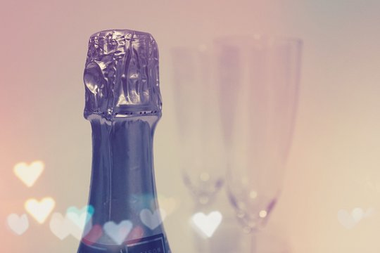 Champagne Bottle with Two Glasses in the Background and Heart Shaped Lens Flares