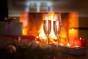 Two glasses with champagne in front of the fireplace. New Year. Christmas.