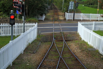 White wooden fence  around level crossing.Railway line crossing road