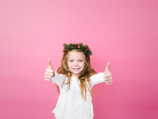 beautiful blond girl with christmas decoration on her head in front of pink background