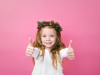 beautiful blond girl with christmas decoration on her head in front of pink background