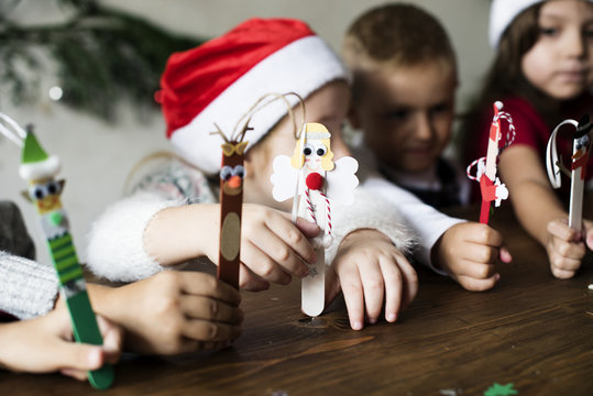 Little kids holding Christmas character decorated popsicle sticks