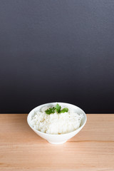 Steamed rice on white bowl wood background