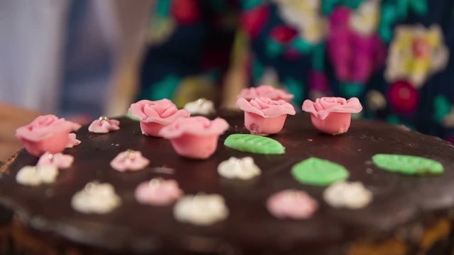 Final touches to the delicious chocolate cake. Putting sweet roses and leaves to home-made sweet.