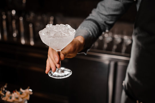Bartender hand holding a cocktail glass with ice