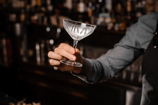 Barman hand holding an empty cocktail glass